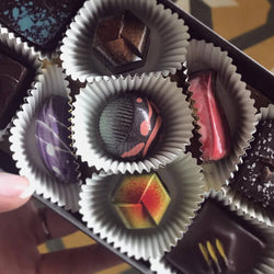 An overhead view of a box of colorful Monsoon Chocolate bon bons