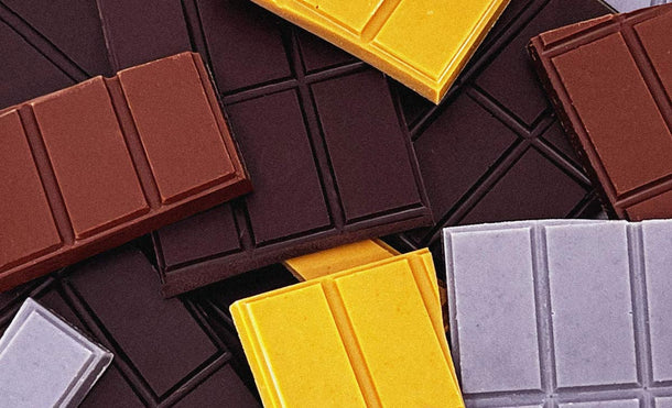 A close up photograph of various colors and flavors of chocolate bars